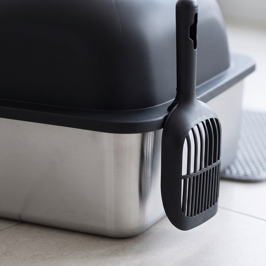 Close view of the stainless steel pan and black lid of the cat litter box with scoop