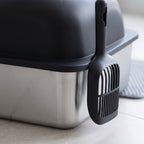 Close view of the stainless steel pan and black lid of the cat litter box with scoop