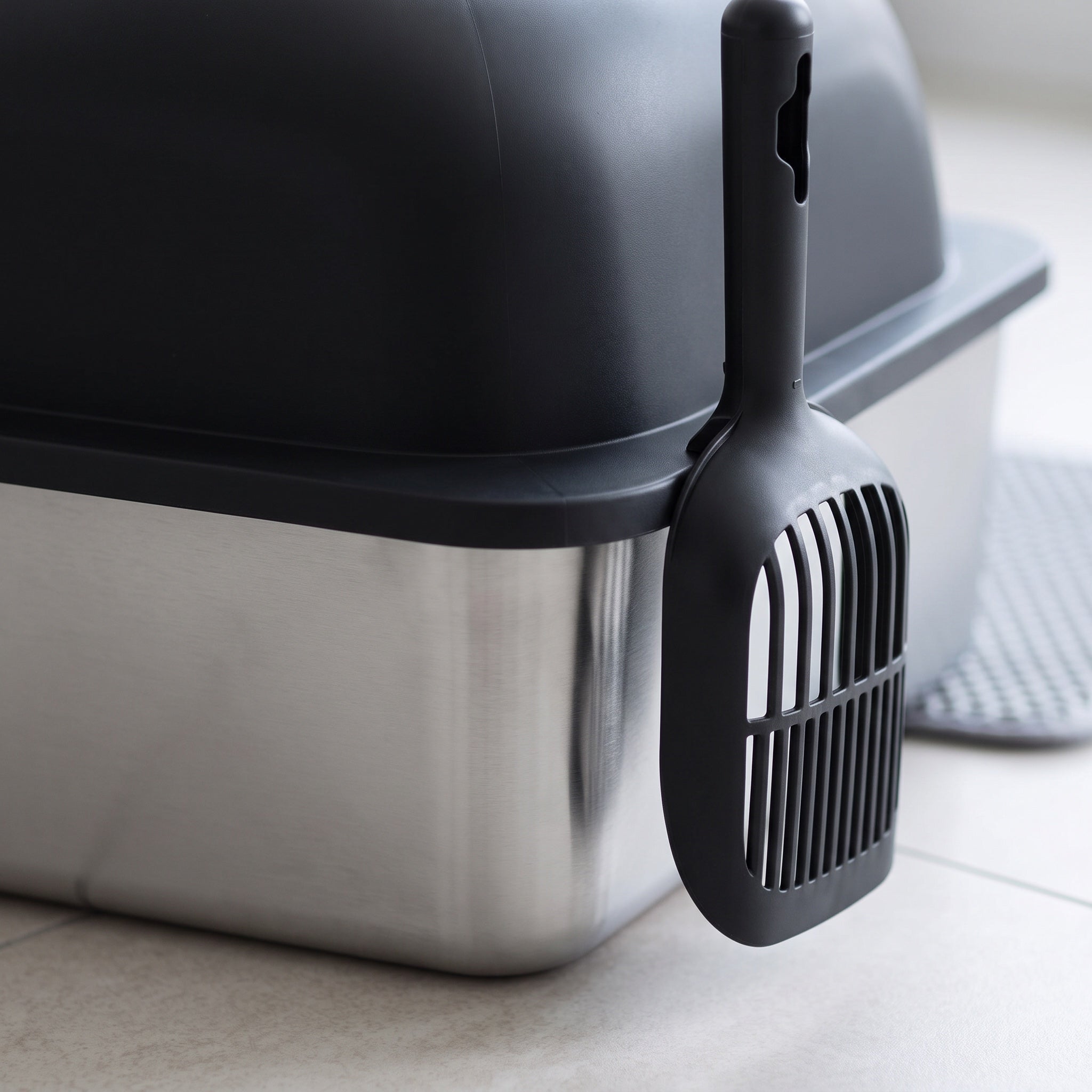 Close view of the stainless steel pan and black lid of the cat litter box with scoop