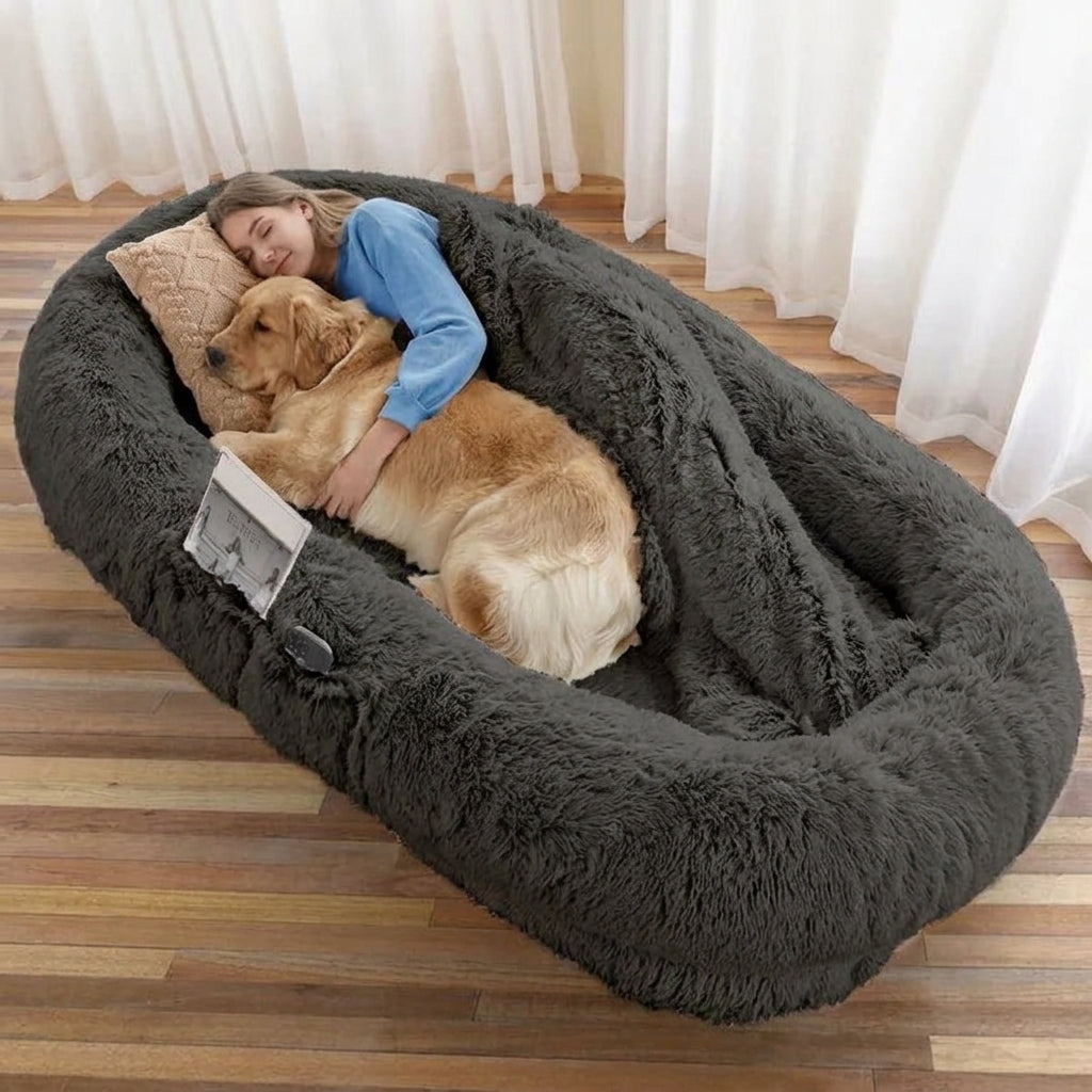 Person and golden retriever resting in the dark grey CalmCurl human dog bed