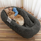 Person and golden retriever resting in the dark grey CalmCurl human dog bed