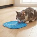 Cat licking the blue CalmCurl lick mat on a kitchen floor